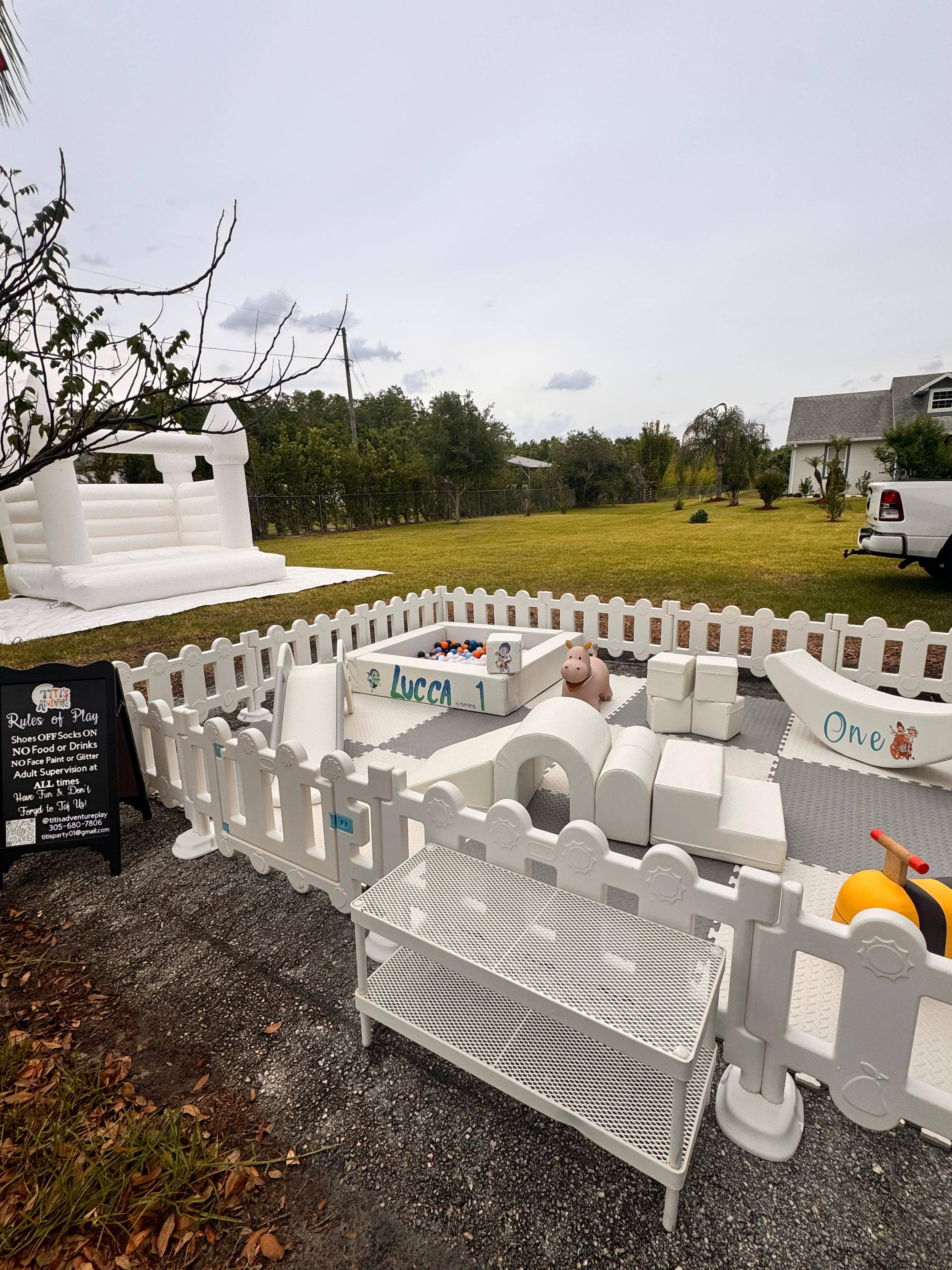 Little Explorer Deluxe outdoor soft play and white bounce house setup with personalized birthday signs in Central Florida