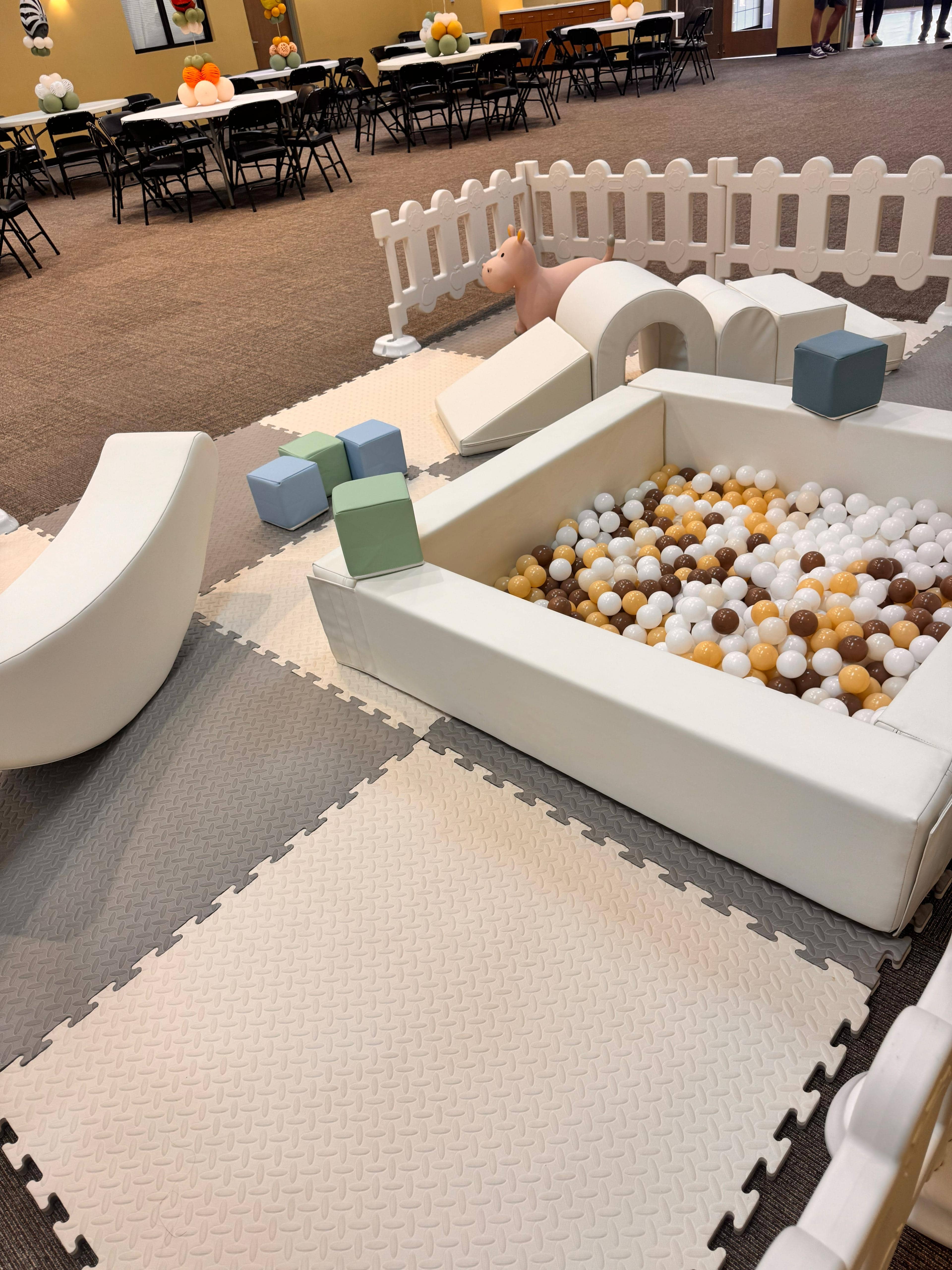 Overhead view of Little Explorer toddler soft play rental — foam mats, ball pit with neutral-tone balls, soft climbers and foam blocks