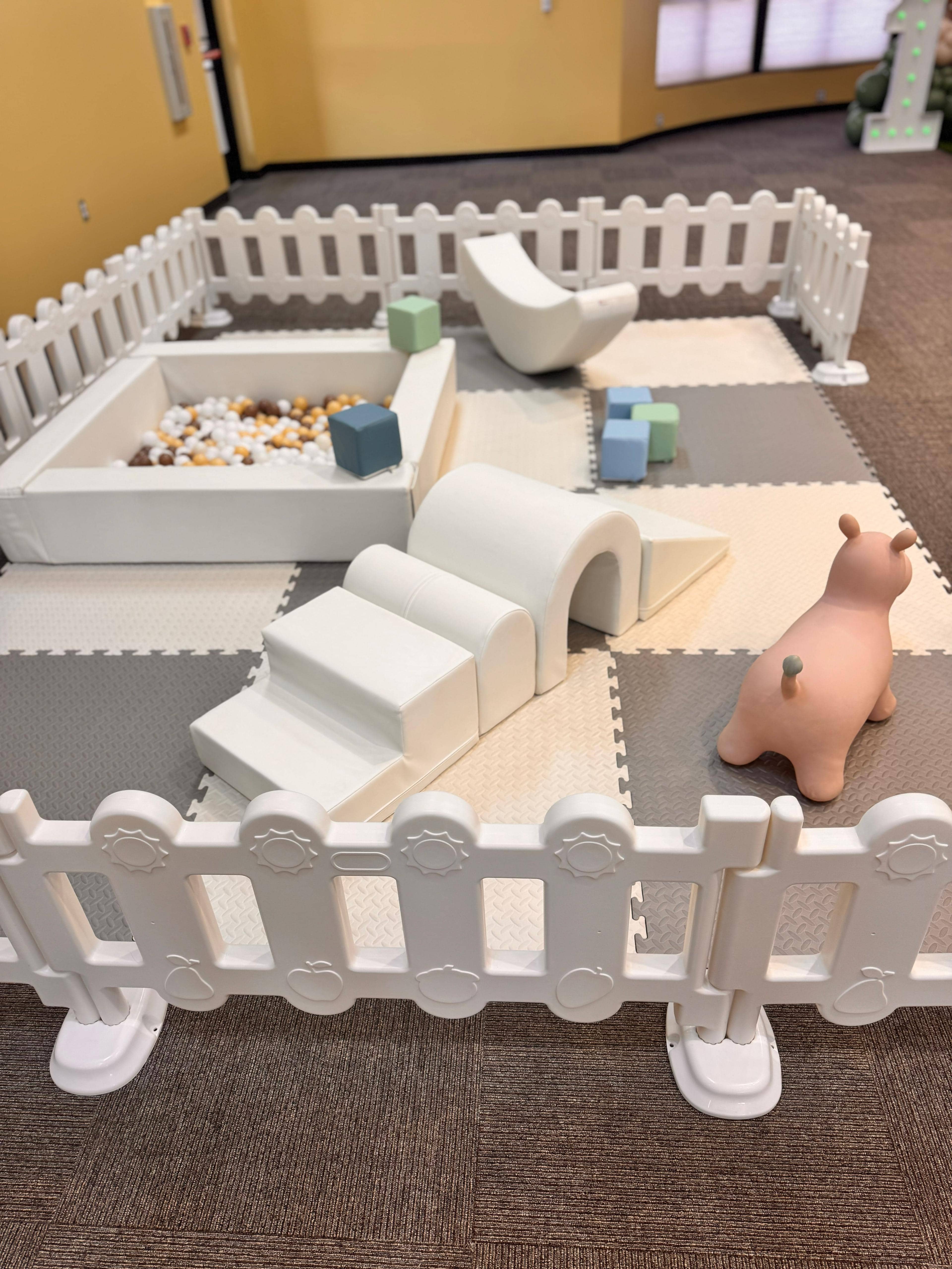 Close-up of Little Explorer soft play rental — foam stair climber, ball pit and white safety fence for kids birthday parties in Central Florida