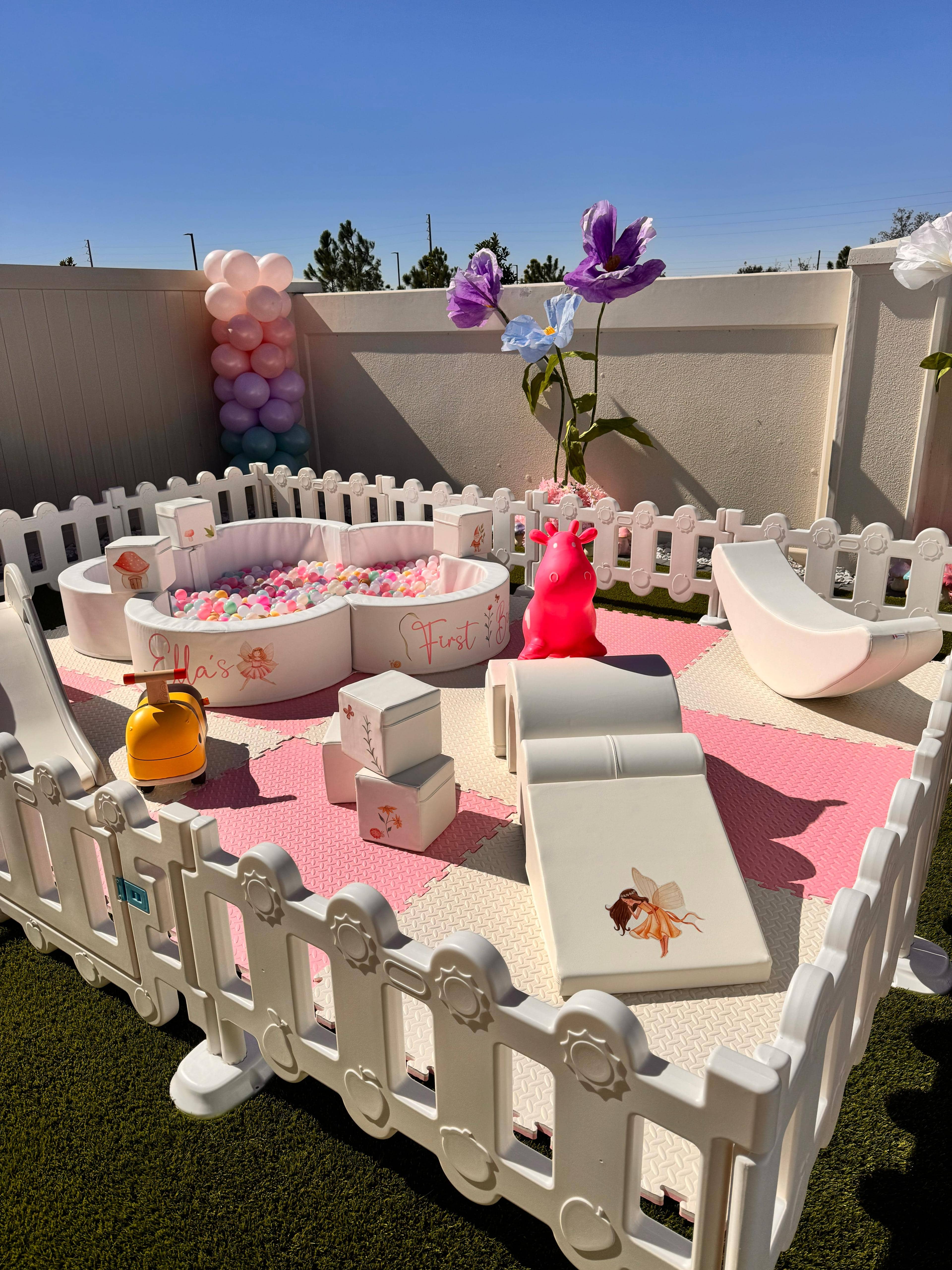 Blush and Bloom outdoor soft play setup with pink foam mats, floral ball pit, pink slide, unicorn inflatable and balloon column
