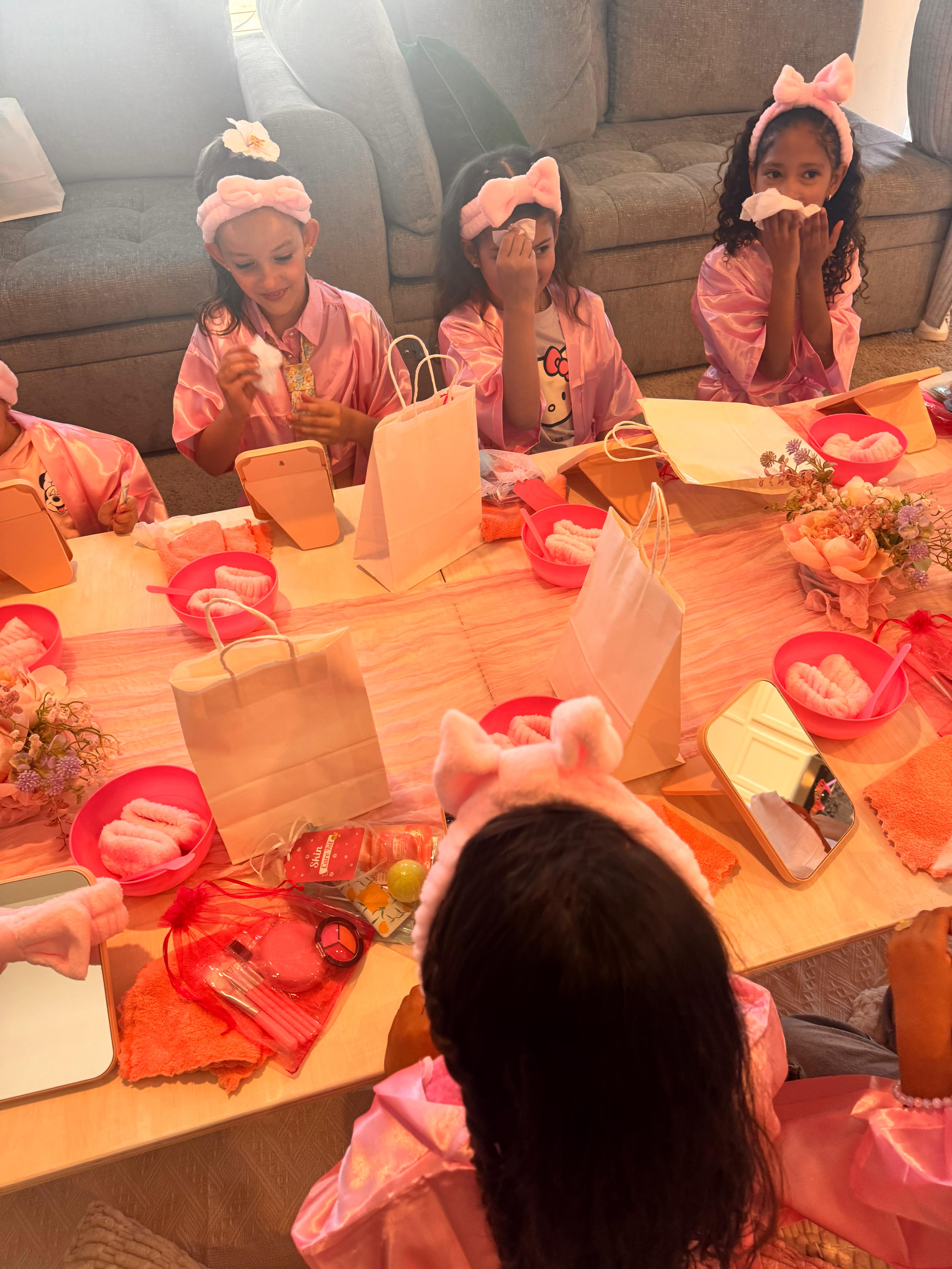 Girls at a Sparkle Spa party, sitting in robes and applying facial masks, smiling and having fun